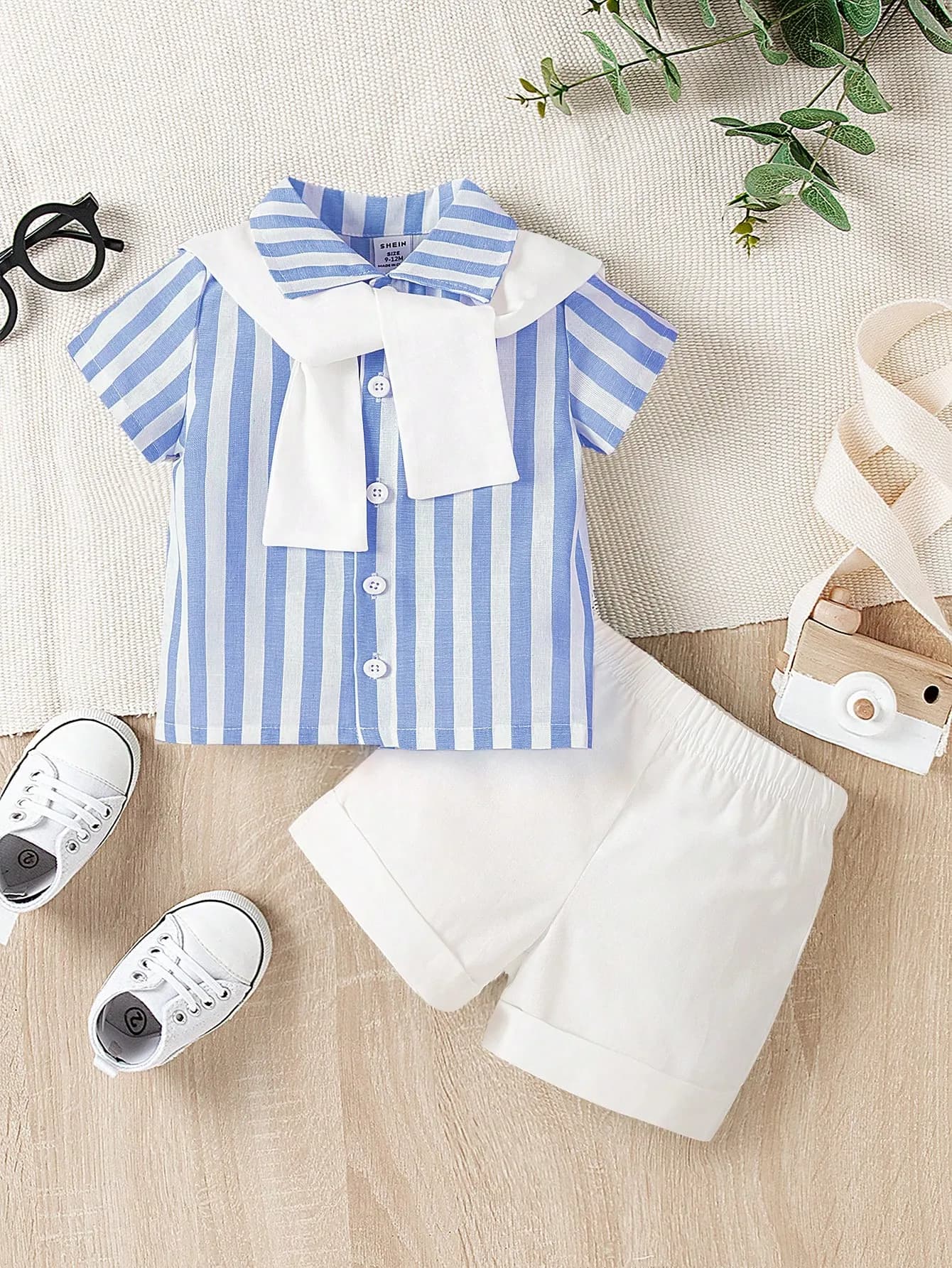 طقم ولادي ذو قميص أزرق مخطط وشورت أبيض ولحشة